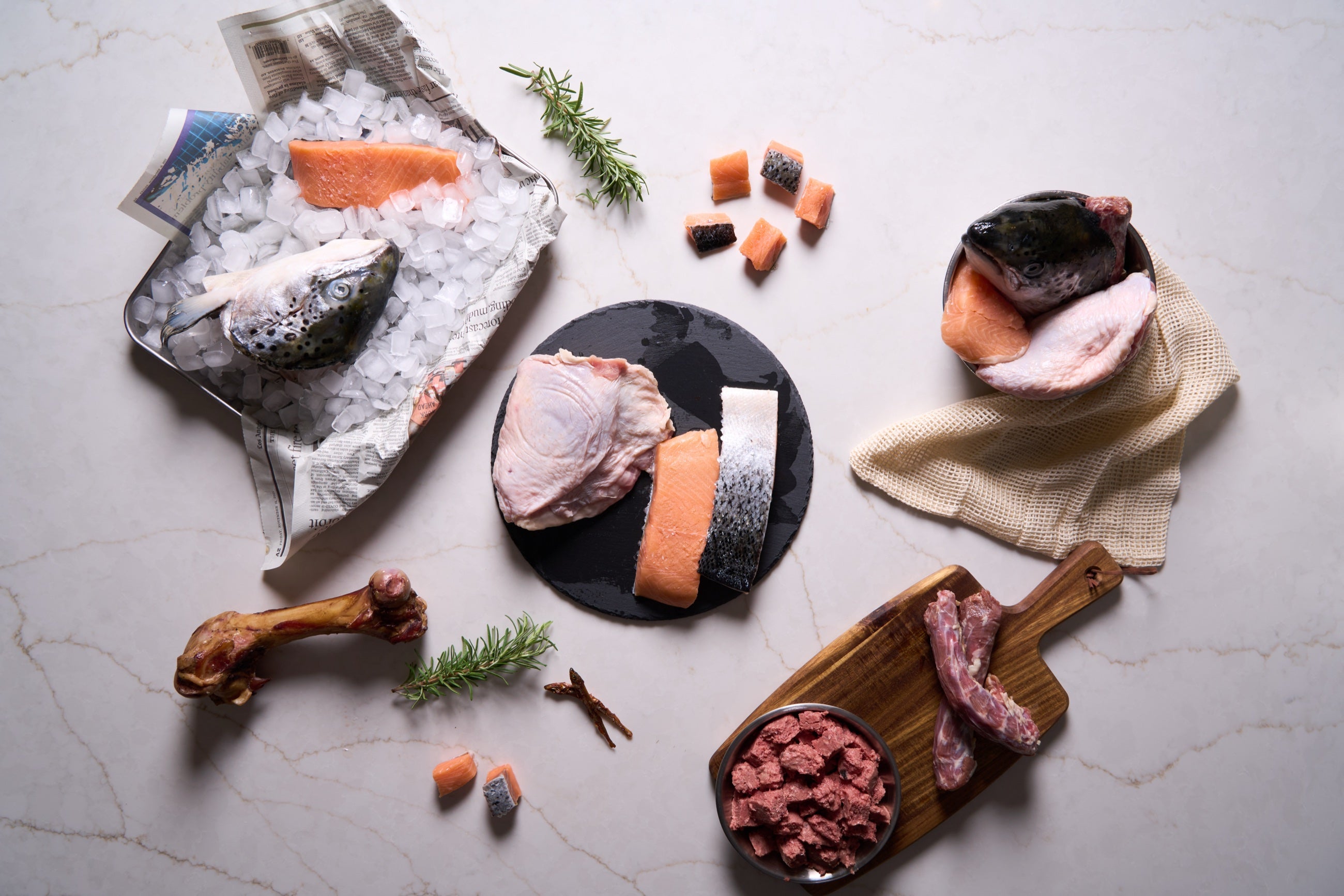 Salmon, poultry, bone, organ, and whole-prey ingredients arranged for a Raw Dawg blend